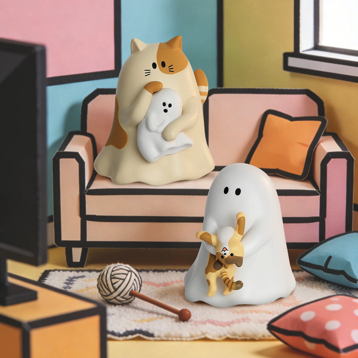 Cream tabby cat cradling a small ghost and a white GHODY ghost on a rug with a ball of yarn